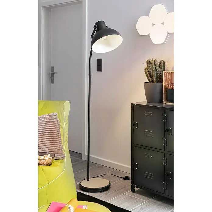 Eglo Lubenham Stehleuchte - Höhe: 160 cm - Eine Stehlampe mit schwarzem Schirm und hellem Sockel beleuchtet ein modernes Interieur mit grünen Akzenten und einem schwarzen Metallschrank.