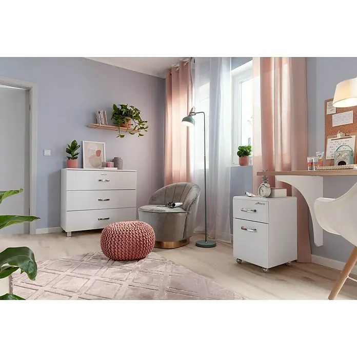 Kayoom Kurzflorteppich Monroe III - Rosa, 150 x 80 cm, 100 % Polyester - Ein gemütliches Zimmer mit einer weißen Kommode, einem bequemen Sessel und einem Strickhocker auf einem rosa Teppich.
