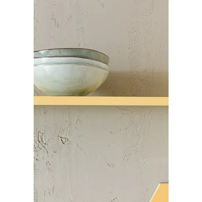 SCHÖNER WOHNEN-Farbe Trendstruktur Effektspachtel Sichtbeton-OptikSichtbeton-Optik, Grau, 16 kg - Eine Nahaufnahme von zwei übereinander gestapelten Keramikschüsseln auf einem gelben Regal vor einer strukturierten Wand.