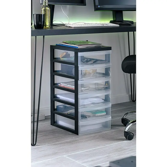 Rollcontainer - L x B x H: 40 x 29 x 106,5 cm, Anzahl Schubladen: 10 Stk., Kunststoff - Eine Aufnahme von einem schwarzen Schrank mit sechs transparenten Schubladen unter einem dunklen Schreibtisch.