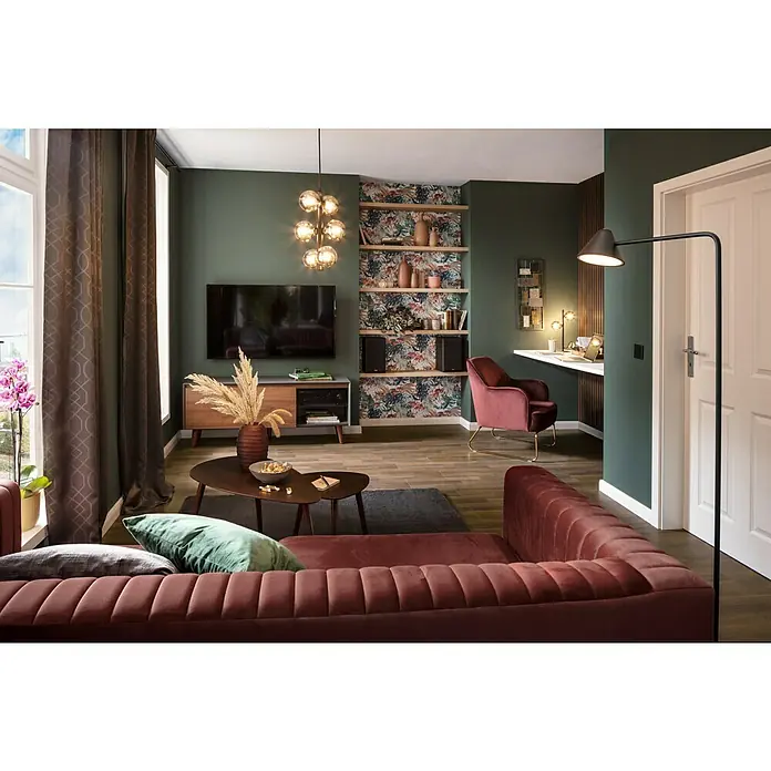 SCHÖNER WOHNEN-Farbe Wandfarbe DesignfarbeBesinnliches Waldgrün, Matt, 1 l, Konservierungsmittelfrei - Einladendes Wohnzimmer mit burgunderrotem Sofa, TV-Bereich und integriertem Arbeitsplatz. Warmes Licht und stilvolle Dekoration schaffen eine gemütliche Atmosphäre.