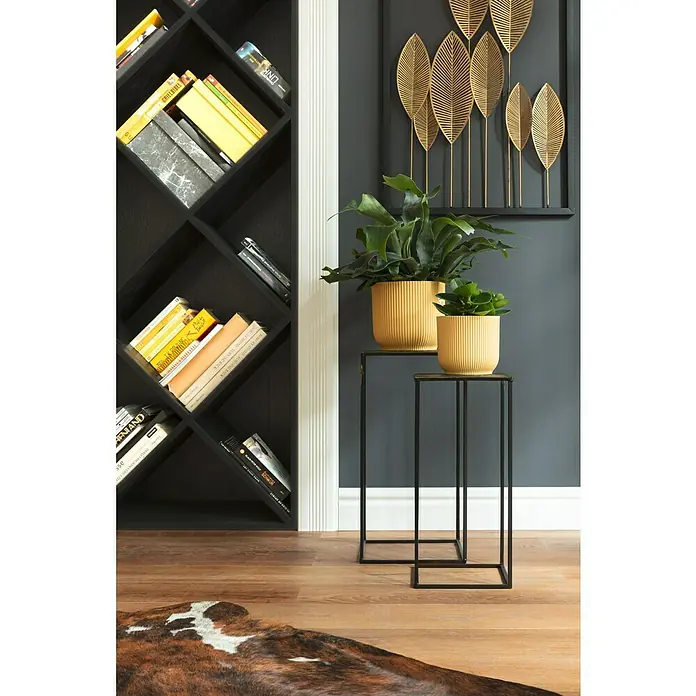 Esbeco Alfombra de piel de vaca - Exótico oscuro, 100% piel auténtica - Interior elegante con estantería, plantas en soportes metálicos y decoración de pared con hojas doradas que crean un ambiente elegante.