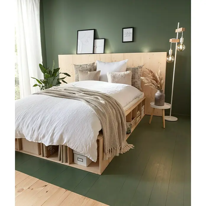 SCHÖNER WOHNEN-Farbe Wandfarbe Designfarbe - Ausgeglichenes Piniengrün, Matt, 2,5 l, Konservierungsmittelfrei - Schlafzimmer mit einem Holzbett mit Stauraum, weißer Bettwäsche und einer Strickdecke vor einer dunkelgrünen Wand.