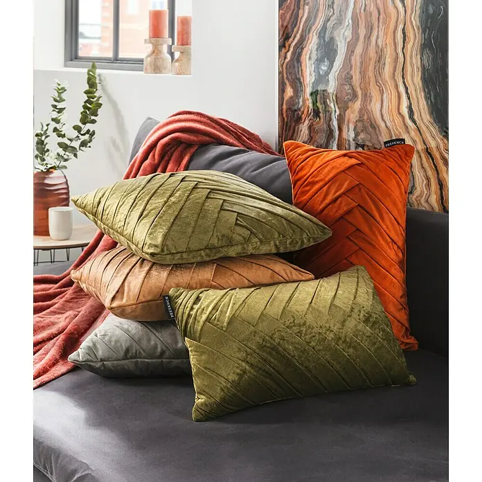 Kissen Folded - Gold, 45 x 45 cm, 100 % Baumwolle - Elegante Dekokissen in Olivgrün, Orange und Kupfer auf einem grauen Sofa arrangiert, sorgen für eine stilvolle und gemütliche Atmosphäre im Wohnraum.