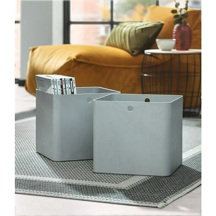 Curver Aufbewahrungsbox Beton L - L x B x H: 28 x 28 x 13 cm, Material: Kunststoff, Beton - Zwei graue Aufbewahrungsboxen mit Zeitschriften auf einem gemusterten Teppich, die eine stilvolle und funktionale Aufbewahrungslösung bieten.