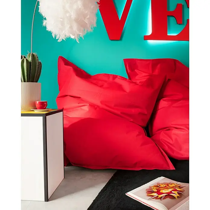 Sitzsack Bigbag Brava - 170 x 130 cm, Tomate, 100 % Polyester/100 % Polyvinylchlorid - Ein rotes Sitzkissen und ein Nachttisch mit Kaktus und Tasse in einem farbenfrohen Raum.