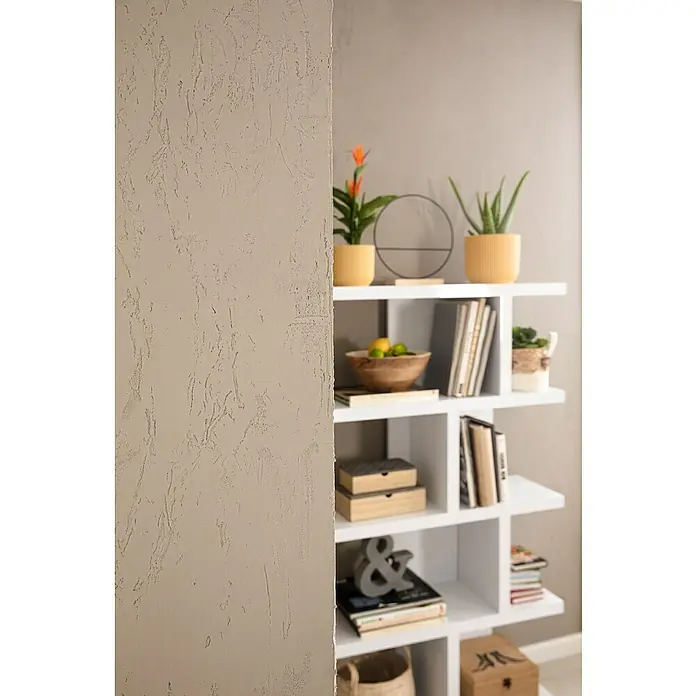 SCHÖNER WOHNEN-Farbe Trendstruktur Dekoputz-Set Sichtbeton-Optik - 3 -tlg. - Nahaufnahme eines modernen weißen Bücherregals mit dekorativen Elementen wie Pflanzen, Büchern und einer Obstschale in einem stilvollen Interieur.