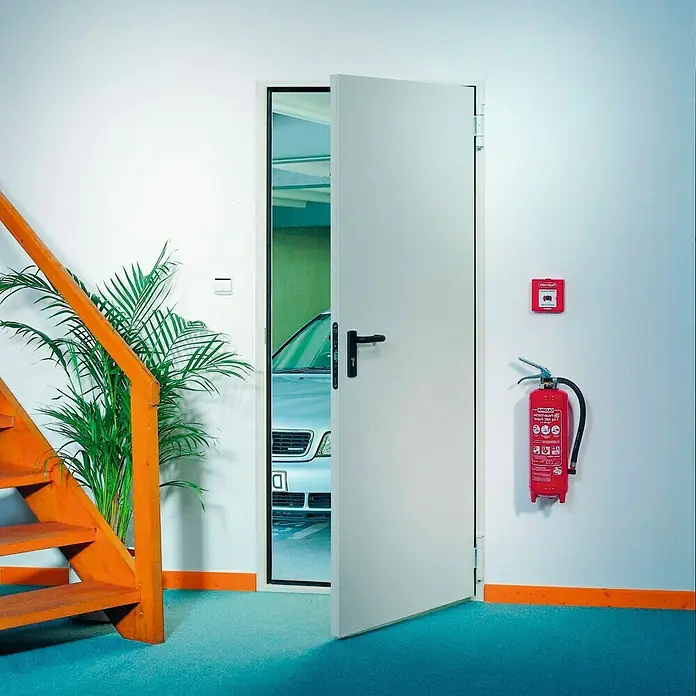 Novoferm Puerta cortafuegos EI2 60 C5 - 88,5 x 203,5 cm, Izquierda, Blanco - Vista de una puerta cortafuegos blanca con manija negra que conduce a un garaje y un extintor al lado.