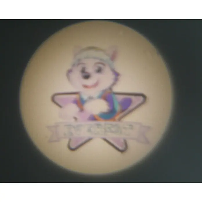 Niermann Taschenlampe Projektor Paw Patrol - Blau, Batteriebetrieben, Kunststoff - Ein runder Aufkleber mit einem Cartoon-Hund, der auf einem lila Stern steht und ein Banner mit dem Text "AY CHEERS" hält.