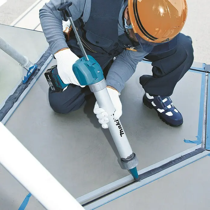 Makita LXT 18V Akku-Kartuschenpresse DCG180ZX - 18 V, Li-Ionen, Ohne Akku - Ein Bauarbeiter verwendet eine Makita Akku-betriebene Kartuschenpistole, um eine Dichtungsmasse aufzutragen.