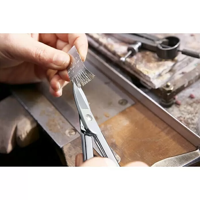 Wisent Goldschmiede-Schere - Geeignet für: Dünnste Bleche, Schnittlänge: 31 mm - Hände schneiden mit einer Silberschere feine Streifen in ein dünnes Metallblech auf einer Werkbank.