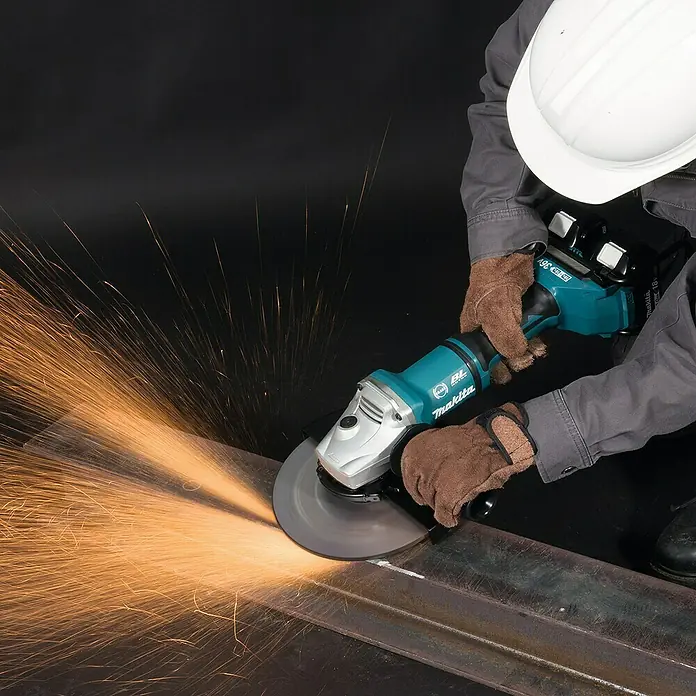 Makita LXT 18V Amoladora angular de batería DGA900ZKX2 - 18 V, Sin batería, Diámetro disco: 230 mm - Un hombre usa una amoladora angular Makita para cortar metal, con chispas volando.