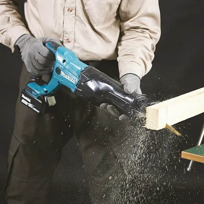Makita LXT 18V Sierra de sable de batería DJR186ZK - 18 V, 1 batería, 5 Ah, Número de carreras marcha en vacío: 0 /min - 2.800 /min - La sierra de sable inalámbrica Makita cortando un trozo de madera, liberando aserrín. Ideal para proyectos de construcción y bricolaje.