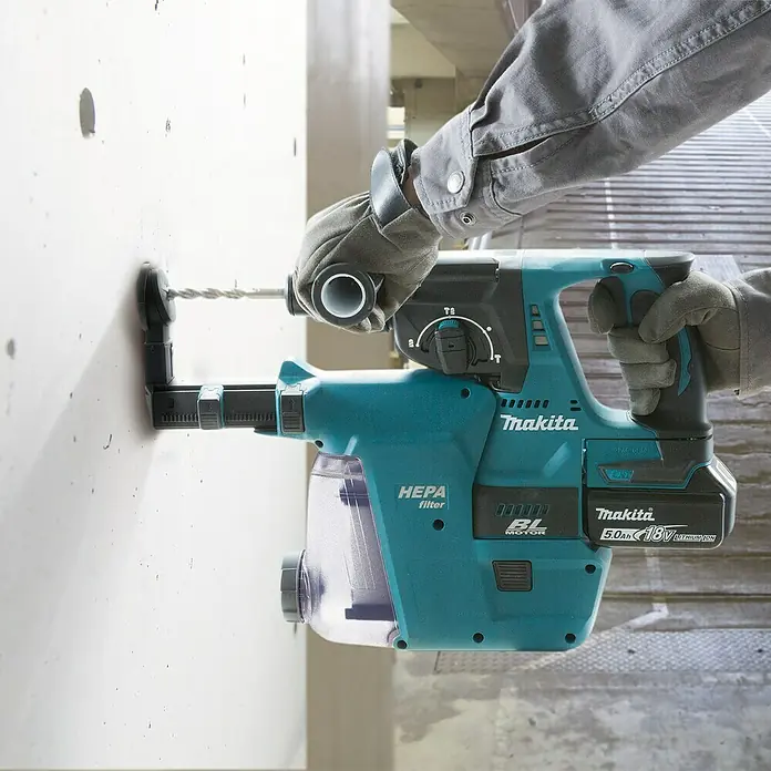 Makita LXT 18V Akku-Kombihammer DHR243RTJ + Artikelnr. 33855482 hinzufügen* - 18 V, 2 Akkus, 5 Ah, 2 J, Ohne Staubabsaugung - Nahaufnahme eines Makita Akku-Bohrhammers mit Staubabsaugung beim Bohren in eine Wand.