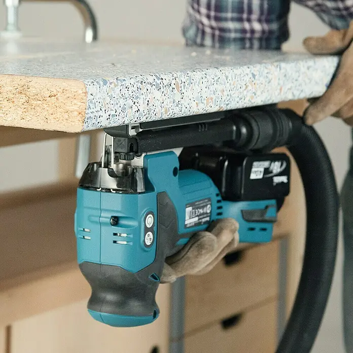 Makita LXT 18V Akku-Pendelhubstichsäge DJV181Z18 V, Li-Ionen, Ohne Akku, 800 /min - 3.500 /min - Eine hellblaue Makita Akku-Stichsäge wird zum Schneiden einer Arbeitsplatte verwendet. Das Gerät verfügt über einen Staubsaugeranschluss.