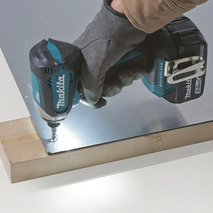 Makita LXT 18V Akku-Schlagschrauber DTD153Z - 18 V, Ohne Akku, 170 Nm - Eine Nahaufnahme eines Makita-Schlagschraubers beim Eindrehen einer Schraube in eine Metallplatte, die auf einem Holzstück liegt.