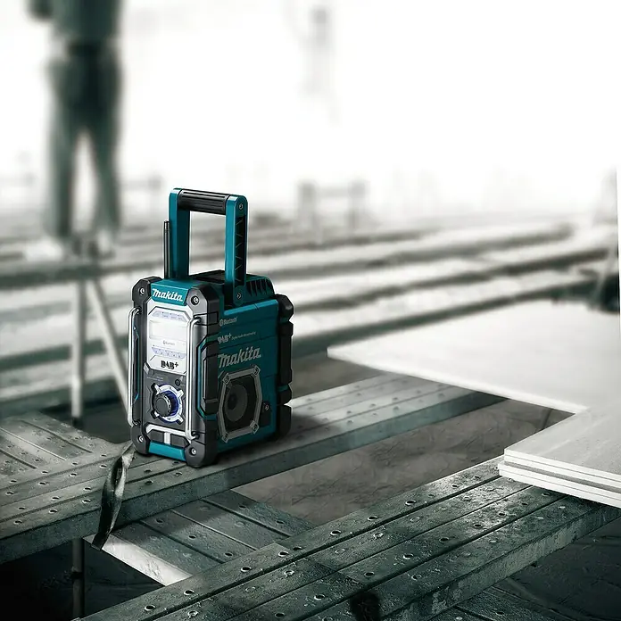 Makita LXT 18V Akku-Baustellenradio DMR112 - 18 V, Ohne Akku, Frequenz: 174.928 - 239.200 MHz (DAB/DAB+) - Nahaufnahme eines Makita Baustellenradios mit Bluetooth und DAB+, das auf einem Baugerüst steht.