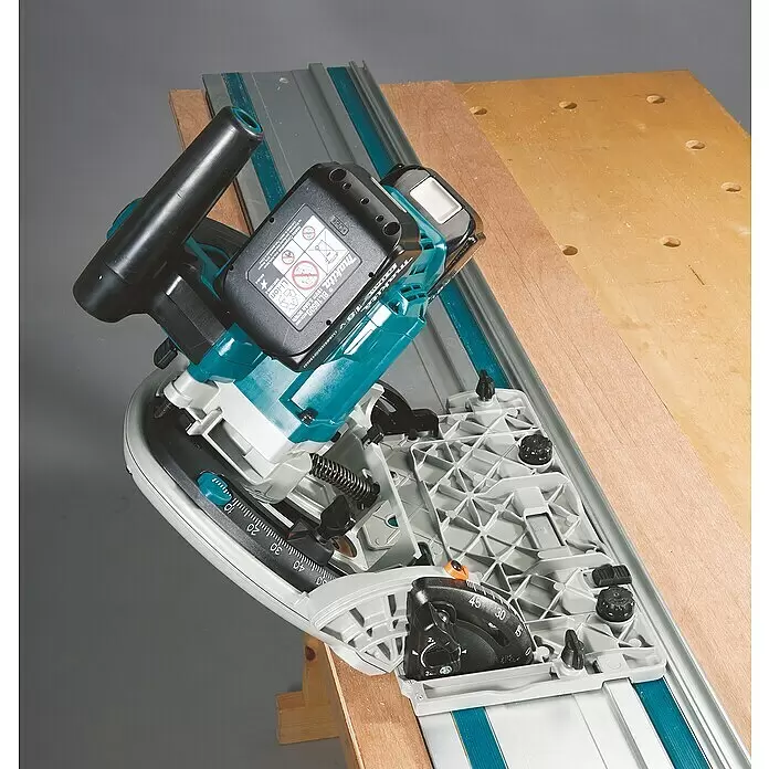 Makita LXT 18V Akku-Tauchsäge DSP601ZJU - 18 V, Ohne Akku, 2.500 U/min - 6.300 U/min - Eine türkise und schwarze Makita Akku-Tauchsäge auf einer Führungsschiene beim Holzschneiden auf einer Werkbank, mit Winkeleinstellungen.