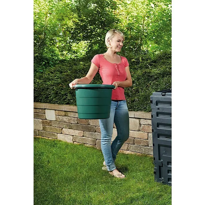 Garantia Tragebehälter - 45 l - Eine Frau hält einen grünen Pflanzkübel vor einem Komposter. Ideal für Gartenarbeiten und Abfallentsorgung.