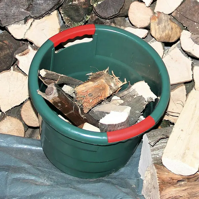 Garantia Tragebehälter - 45 l - Ein grüner Eimer mit roten Griffen, gefüllt mit Holz, vor einem Stapel Holzscheite.