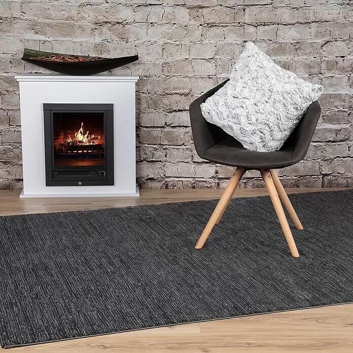 Kissen Smooth - Schwarz, 45 x 45 cm, 100 % Polyester - Dunkelgrauer strukturierter Teppich auf Holzboden im Wohnzimmer, ergänzt Kamin und Stuhl.