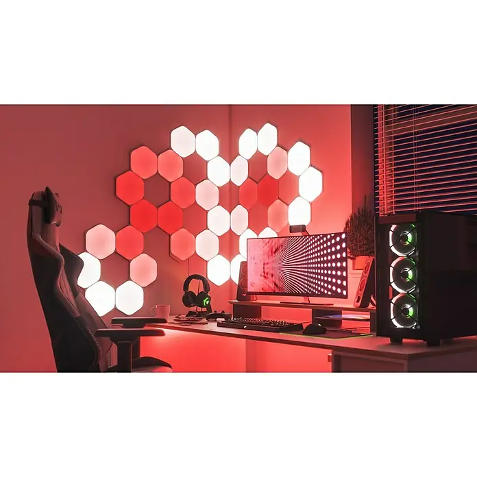 Nanoleaf Erweiterungskit Shapes Hexagons 3 Panels - 3 Stk., Weiß, RGBW, Hexagons, Smart Home-fähig: Ja - Ein Gaming-Setup mit anpassbaren LED-Panels an der Wand, einem PC-Turm mit RGB-Lüftern und einem Gaming-Stuhl, alles in roter Beleuchtung.