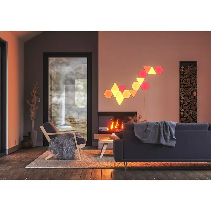Nanoleaf Erweiterungskit Shapes Hexagons 3 Panels - 3 Stk., Weiß, RGBW, Hexagons, Smart Home-fähig: Ja - Ein gemütliches Wohnzimmer mit einem Nanoleaf Lichtpaneel an der Wand, das eine warme Atmosphäre erzeugt.