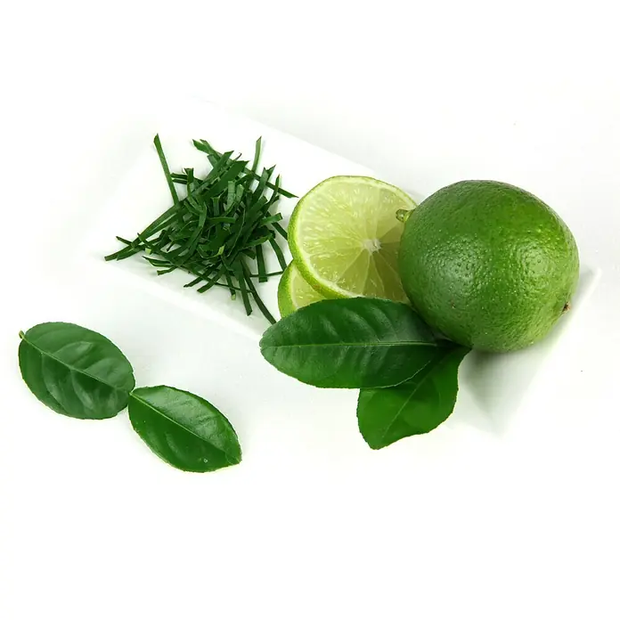 Blu Bio Kaffir-Limettenbaum - Citrus hystrix, Weiß, Topfgröße: 12 cm - Eine Nahaufnahme von Limetten, Limettenscheiben, fein gehackter Limettenschale und Limettenblättern auf einem weißen Teller, erfrischend und aromatisch.