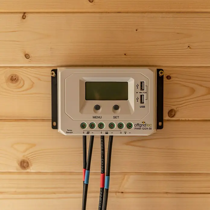 Offgridtec Batteriekabel - Länge: 1,5 m, Schwarz - Nahaufnahme eines Offgridtec PWM-12/24-30 Solarreglers an einer Holzwand, der Stromversorgung und Steuerung für Solaranlagen bietet.