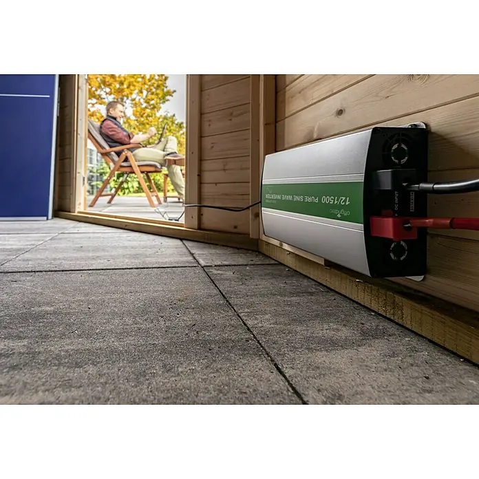 Offgridtec Spannungswandler PSI 12-1500 - Ausgangsspannung: 230 V - Eine Nahaufnahme eines Offgridtec 12/1500 Pure Sine Wave Inverters, der an einer Holzwand montiert ist und mit Kabeln verbunden ist.