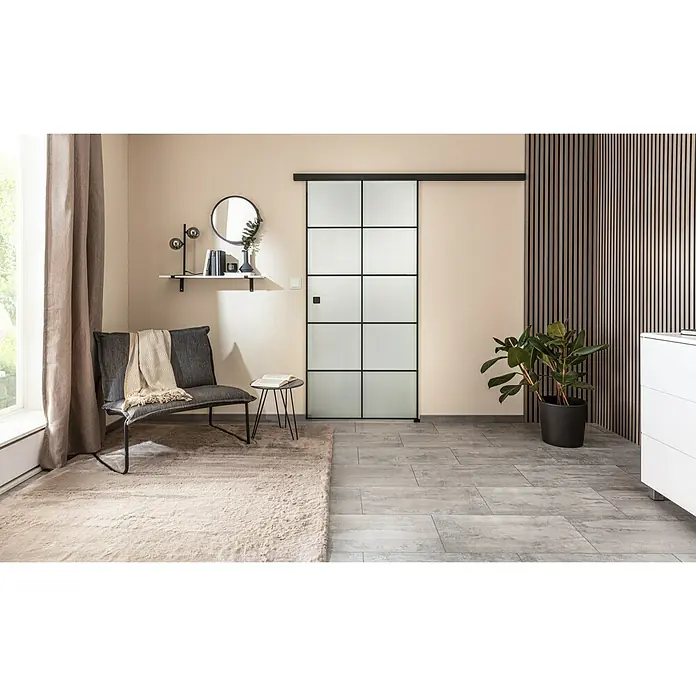 Diamond Doors Black Edition Schiebetür-Komplettset Loft - 935 x 2.058 mm, Milchglas - Modernes Interieur mit einer Glasschiebetür mit schwarzem Rahmen, die Helligkeit und Stil in den Raum bringt. Bequemer Sessel und dekorative Elemente.