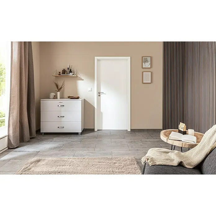 GetaDoor Laminit Türzarge GL 222 - 860 x 1.985 mm, Wandstärke: 100 mm, DIN Anschlag: Links, Arctic Weiß - Ein moderner Raum mit einer weißen Kommode mit drei Schubladen, einer weißen Tür und einem stilvollen Wandpaneel.
