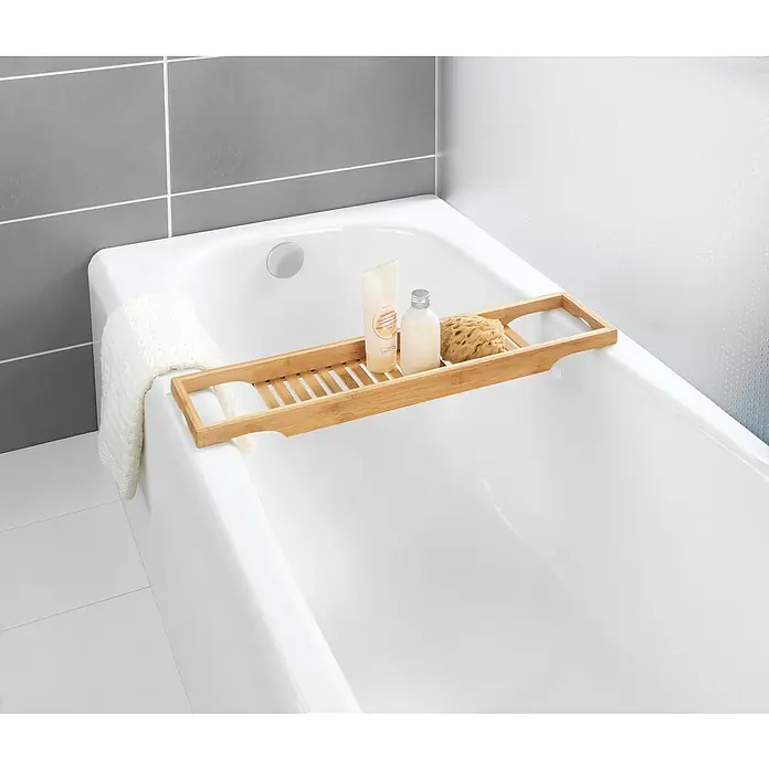 Wenko Bambusa Ablage - L x B x H: 16 x 70 x 4,5 cm, Bambus, Bambus - Ein weißes Bad mit einer Badewannenablage aus Bambus, die mit Badartikeln wie Lotion, Seife und einem Badeschwamm dekoriert ist.