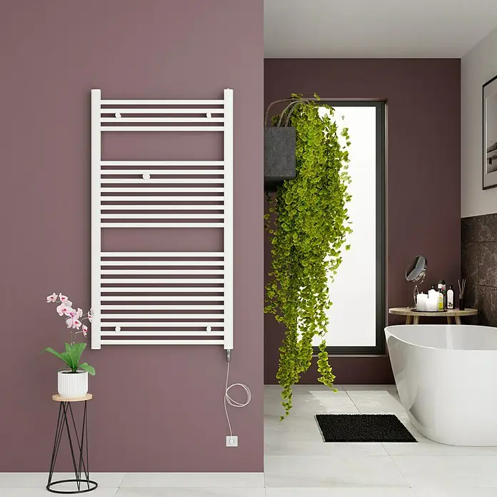 Admiral Elektro-Badheizkörper Berlin - B x H: 600 x 1.270 mm - Elegantes Badezimmer mit einem weißen Handtuchwärmer an einer lila Wand, ergänzt durch grüne Pflanzen und eine stilvolle Badewanne.