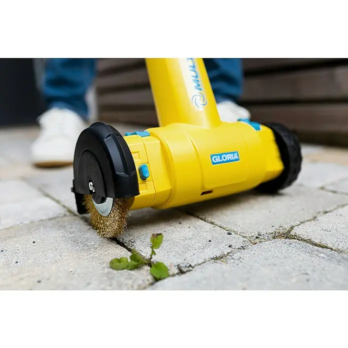 Gloria Power for All 18V Bodenreinigungsbürste MultiBrush li-on Plus - 18 V, Ohne Akku, Akkutyp: Li-Ionen, 450 U/min - 1.260 U/min - Nahaufnahme einer gelben Gloria MultiBrush, die Unkraut aus Pflastersteinen entfernt.