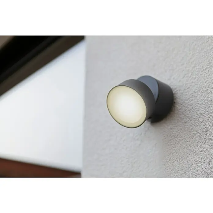 Lutec LED-Außenwandleuchte - 6,7 W, Anthrazit - Nahaufnahme einer modernen, grauen Wandleuchte mit warmem Lichtschein an einer strukturierten Wand.