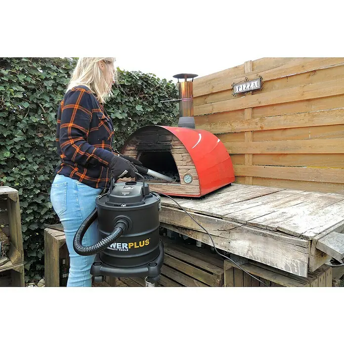 PowerPlus Aspirador de cenizas eléctrico POWX308 - 1.200 W, Volumen de recipiente: 20 l, Sin bolsa - Una mujer limpia un horno de pizza con un aspirador de cenizas POWERPLUS, ideal para una eliminación rápida y limpia de cenizas.