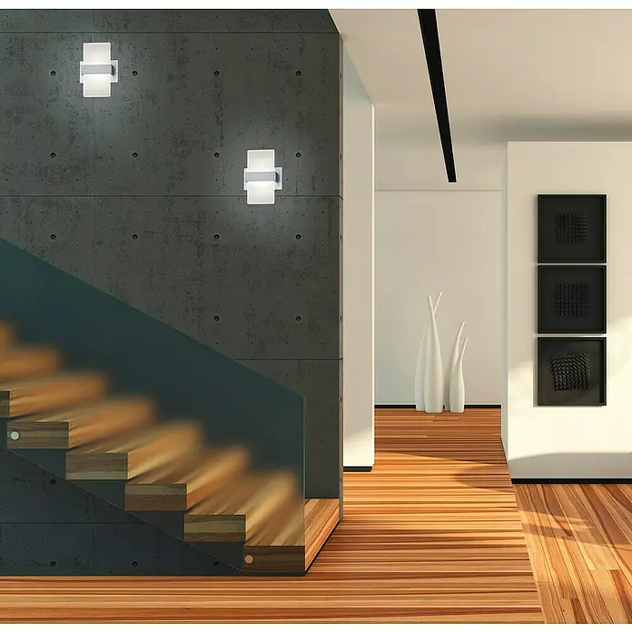 Reality Leuchten LED-Wandleuchte Platon - 4 W, L x B x H: 9 x 13 x 18 cm, Aluminium, Warmweiß - Moderne Wandleuchten zieren eine Betonwand neben einer Holztreppe, die ein stilvolles und modernes Interieur hervorhebt.