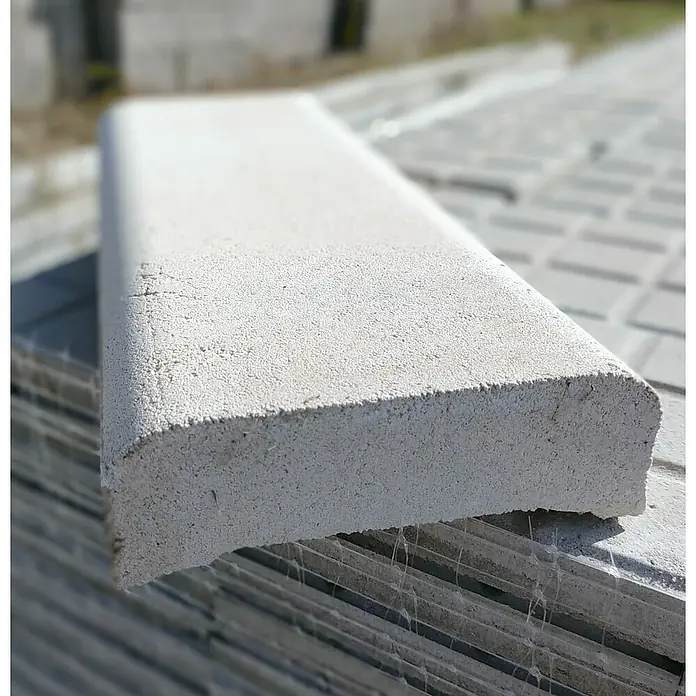 BHS Cataluña Cubremuros Jaen - 50 x 15 x 6 cm, Blanco, Hormigón - Primer plano de un bordillo gris con un borde redondeado, apilado con otros bordillos. Ideal para proyectos de jardín y paisajismo.