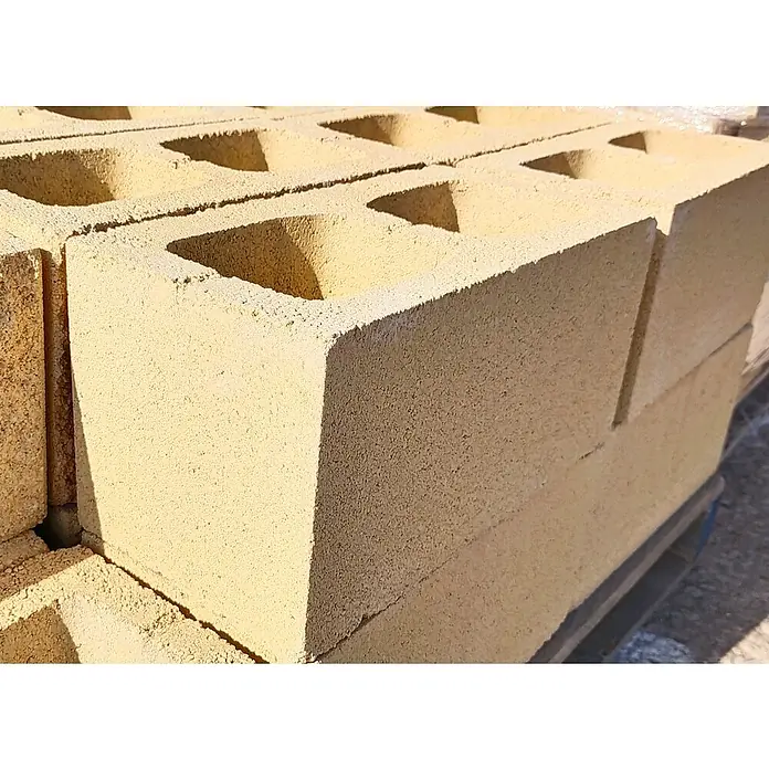 BHS Cataluña Bloque de hormigón poroso caravista - 40 x 20 x 20 cm, Crema, Hormigón - Primer plano de bloques de cemento amarillos con agujeros rectangulares, apilados en un patrón sobre un palet, ideales para construcción.