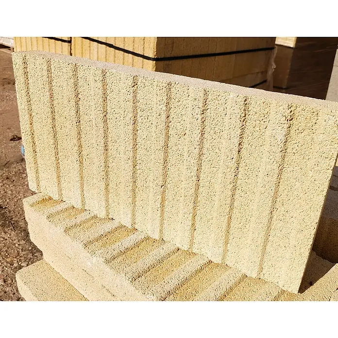 BHS Cataluña Pavimento plaqueta ranurada - 50 x 24,5 cm, Crema - Primer plano de una pila de bloques de hormigón amarillos, listos para proyectos de construcción, que muestra una textura distinta.