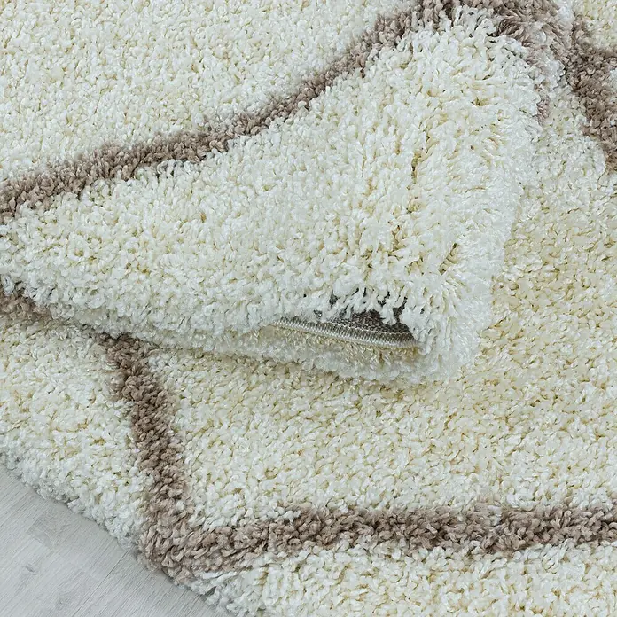 Hochflorteppich Alvor 3401 - Cream, 250 x 80 cm, 100 % Polypropylen - Detailaufnahme eines cremefarbenen Shaggy-Teppichs mit braunen Akzenten, der eine weiche und einladende Textur zeigt.