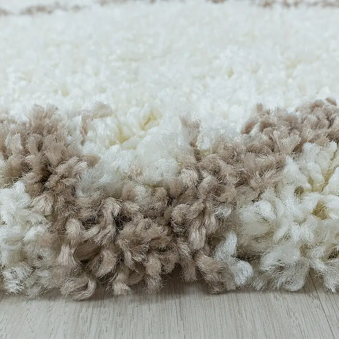 Hochflorteppich Alvor 3401 - Cream, 250 x 80 cm, 100 % Polypropylen - Nahaufnahme eines flauschigen, gestreiften Teppichs in Weiß- und Beigetönen, der eine weiche und einladende Textur zeigt.