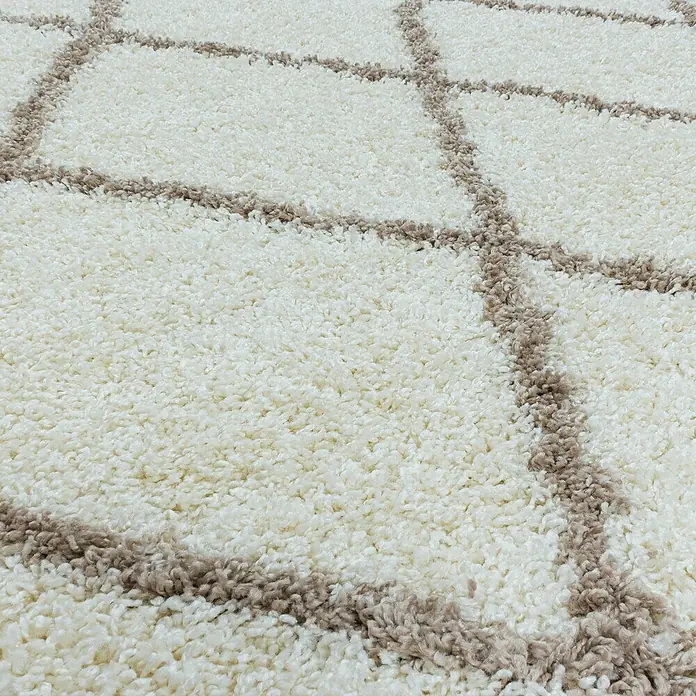 Hochflorteppich Alvor 3401 - Cream, 250 x 80 cm, 100 % Polypropylen - Nahaufnahme eines cremefarbenen Teppichs mit einem abstrakten, braunen Muster, das eine weiche und einladende Textur zeigt.