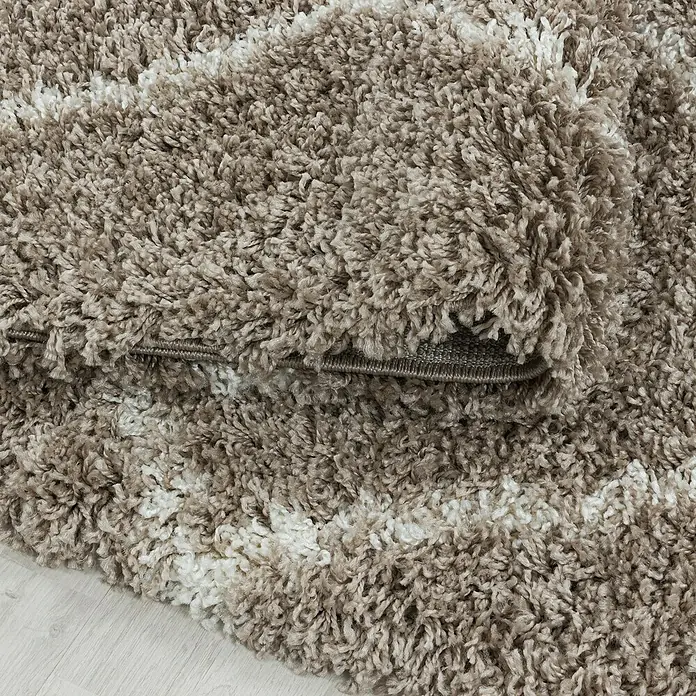 Hochflorteppich Alvor 3401Beige, 370 x 280 cm, 100 % Polypropylen - Nahaufnahme eines beigen Shaggy-Teppichs mit weißen Akzenten, der eine weiche und luxuriöse Textur hervorhebt.\n
