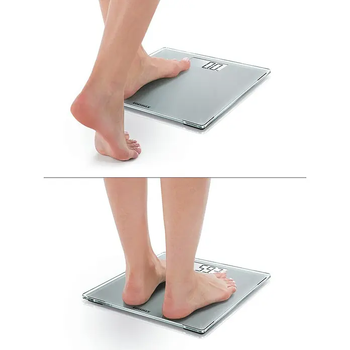 Báscula digital Style Sense Compact 300 - 29 x 29 x 2 cm, Vidrio, Plata - Una persona está de pie sobre una báscula digital Soehnle que muestra 59,7 kg. La báscula tiene un diseño elegante y moderno con superficie de cristal.