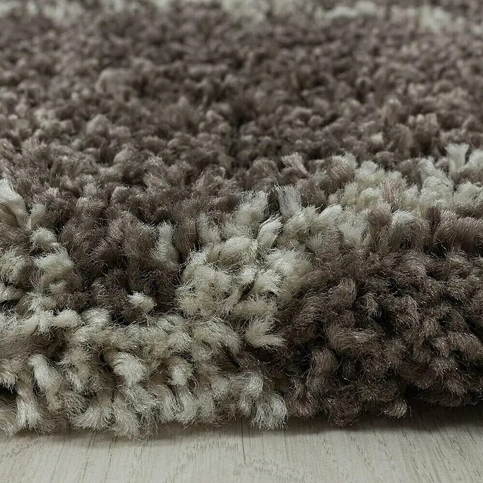 Hochflorteppich Alvor 3401Taupe, Durchmesser: 160 cm, 100 % Polypropylen - Nahaufnahme eines braun-weißen Zottelteppichs, der eine weiche Textur und Farbvariationen zeigt. Ideal für Wohnkomfort.
