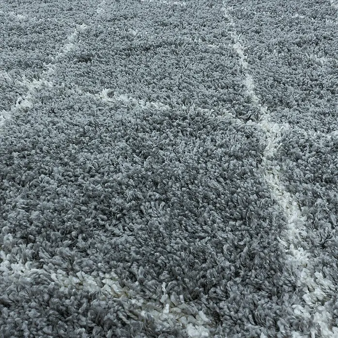Hochflorteppich Alvor 3401 - Grau, Durchmesser: 160 cm, 100% Polypropylen - Nahaufnahme eines grauen Shaggy-Teppichs mit weißem geometrischen Muster, der eine weiche Textur und ein modernes Design zeigt.