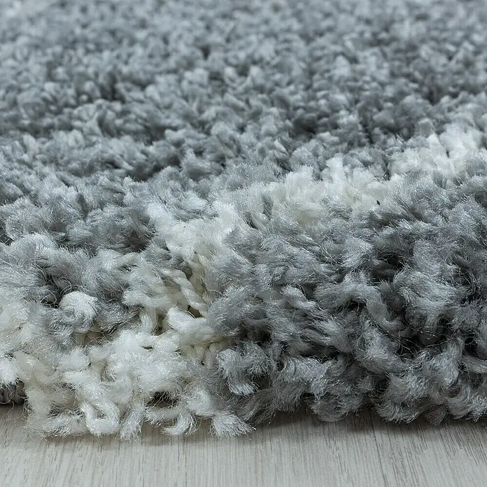 Hochflorteppich Alvor 3401Grau, Durchmesser: 120 cm, 100 % Polypropylen - Nahaufnahme eines grauen und weißen Shaggy-Teppichs. Weicher, flauschiger Teppichboden für ein gemütliches Zuhause.