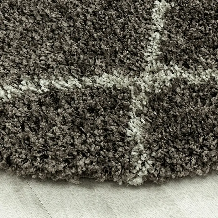 Hochflorteppich Alvor 3401Taupe, Durchmesser: 160 cm, 100 % Polypropylen - Nahaufnahme eines grauen Teppichs mit weißem Muster, der eine weiche und einladende Textur zeigt.